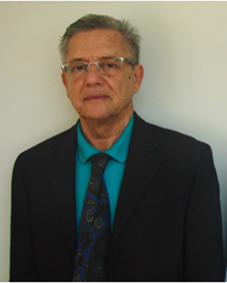 A man in a suit and tie standing against a wall.