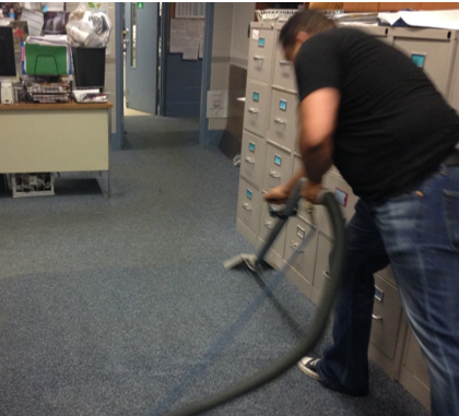 A man is vacuuming the floor in an office.